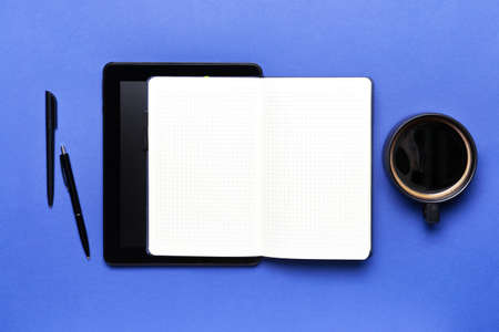 Notebook with tablet computer and cup of coffee on color background