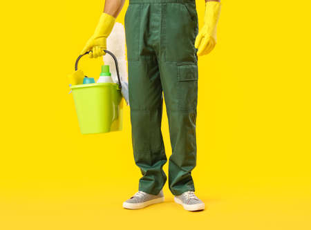 Young male janitor with cleaning supplies on color backgroundの写真素材