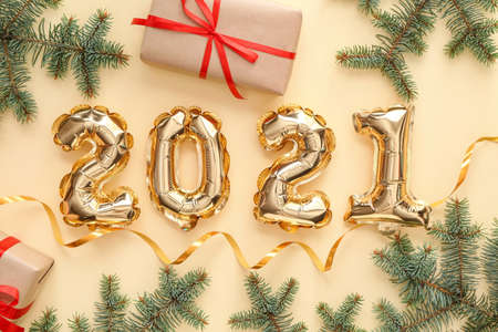 Balloons in shape of figure 2021, Christmas gift and fir branches on color background