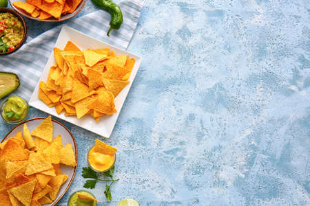 Plates with tasty nachos and sauces on color backgroundの写真素材