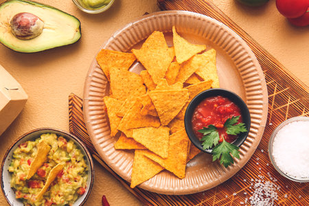 Plate with tasty nachos and sauces on color backgroundの写真素材