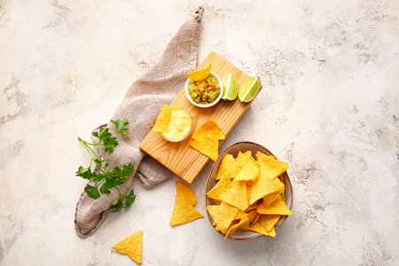 Tasty nachos in plate and board with sauces on light backgroundの写真素材