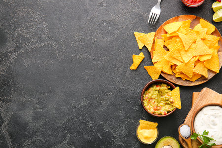 Plate with tasty nachos and products on dark backgroundの写真素材
