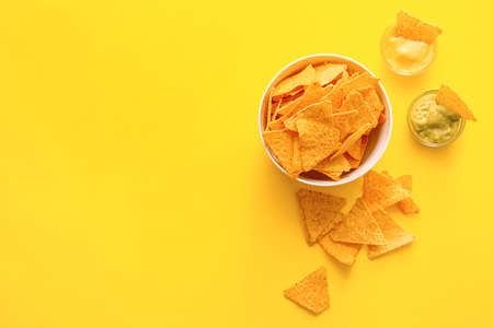 Bowl with tasty nachos and sauces on color backgroundの写真素材