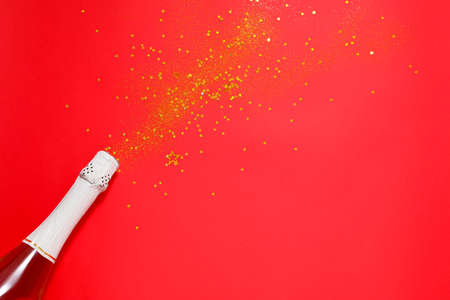 Bottle of champagne and glitters on color background. New Year celebrationの写真素材