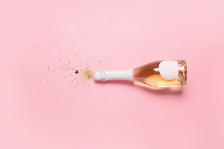 Bottle of champagne and glitters on color background. New Year celebrationの写真素材
