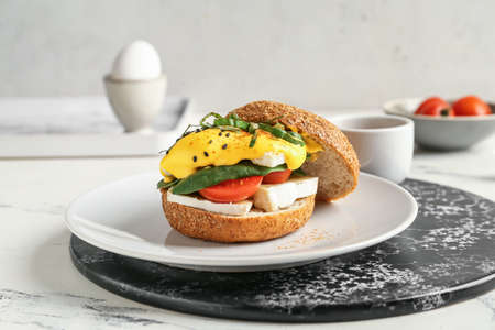 Plate with tasty burger and florentine egg on light backgroundの写真素材