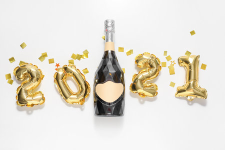 Balloons in shape of figures and bottle of champagne on white background. New year celebrationの写真素材