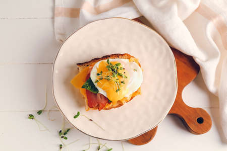Tasty sandwich with florentine egg and bacon on light background