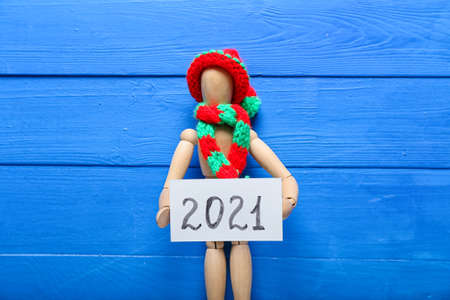 Wooden human figure holding paper with figure 2021 on color backgroundの写真素材