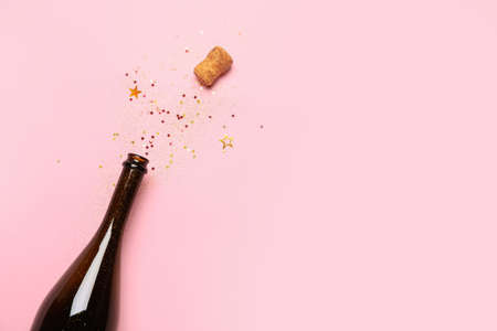 Bottle of champagne and glitters on color background. New year celebrationの写真素材