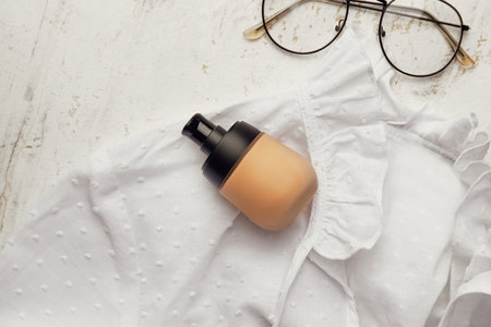 Bottle of makeup foundation and glasses on light backgroundの写真素材