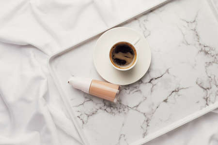 Makeup foundation in bottle and cup of coffee on fabric backgroundの写真素材