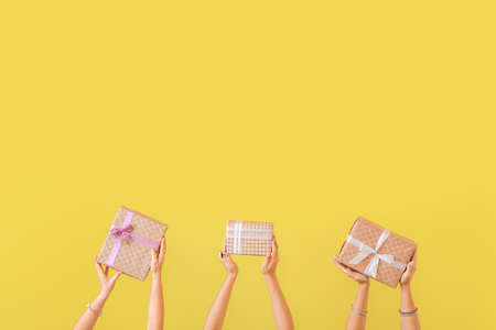 Hands with gift boxes on color backgroundの写真素材