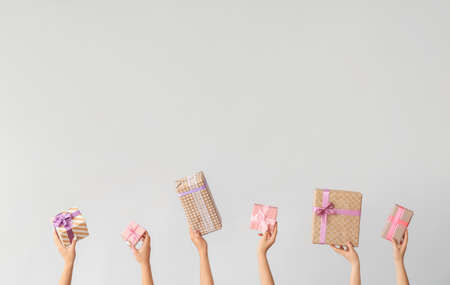 Hands with gift boxes on light backgroundの写真素材