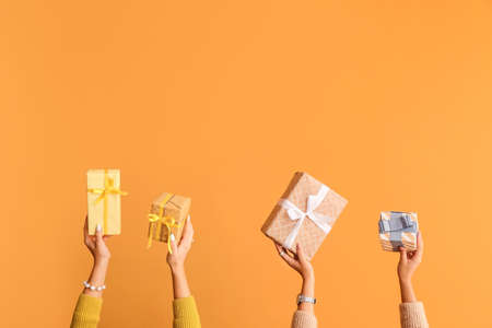 Hands with gift boxes on color backgroundの写真素材