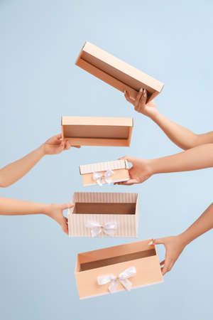Hands with gift boxes on color background