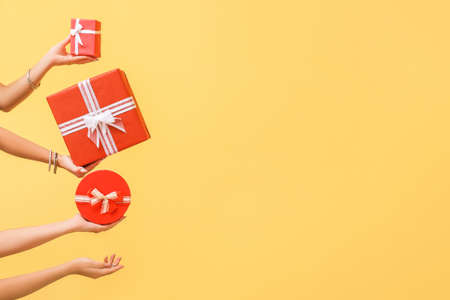 Hands with gift boxes on color background