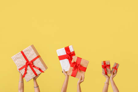 Hands with gift boxes on color backgroundの写真素材