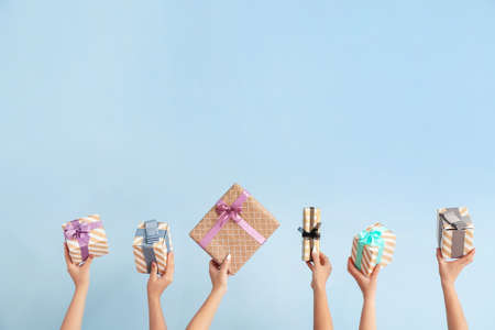Hands with gift boxes on color backgroundの写真素材