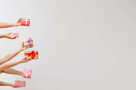 Hands with gift boxes on light backgroundの写真素材