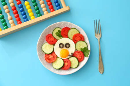 Creative breakfast for children with egg and fresh vegetables on color background
