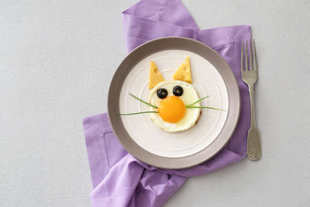 Creative breakfast for children with egg, cheese and olives on light background