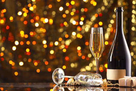 New Year composition with champagne against blurred lightsの写真素材
