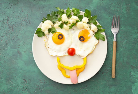 Creative breakfast for children with eggs and fresh vegetables on color backgroundの写真素材