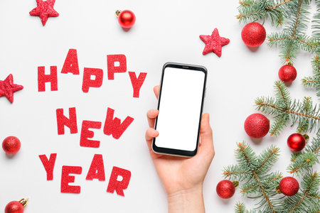 Hand with mobile phone and New Year composition on light backgroundの写真素材