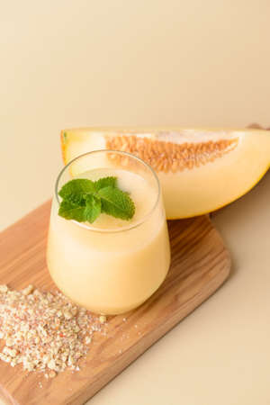 Glass with melon smoothie on color background