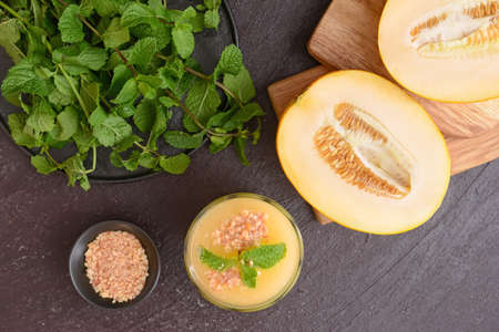 Glass with melon smoothie on dark wooden background