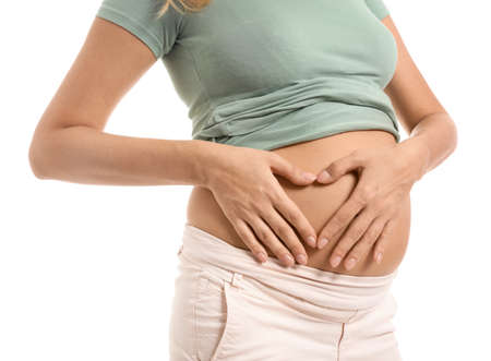 Beautiful pregnant woman making heart with her hands on white backgroundの写真素材