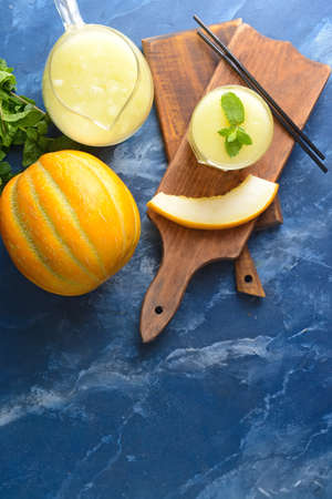 Glass and jug with melon smoothie on color backgroundの写真素材