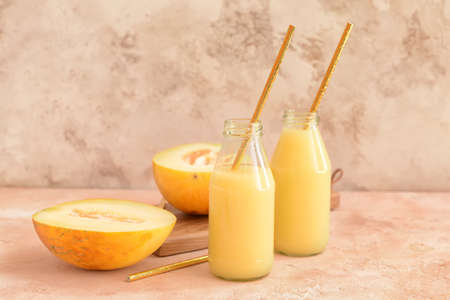 Bottles with melon smoothie on color backgroundの写真素材