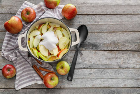 Cooking pot with cut apple and sugar on wooden backgroundの写真素材