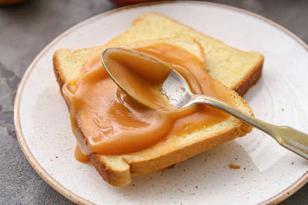 Toasts and spoon with sweet apple jam on dark backgroundの写真素材