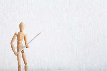Wooden mannequin with pencil on white backgroundの写真素材