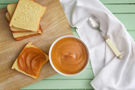 Bowl with sweet apple jam and toasts on color wooden background