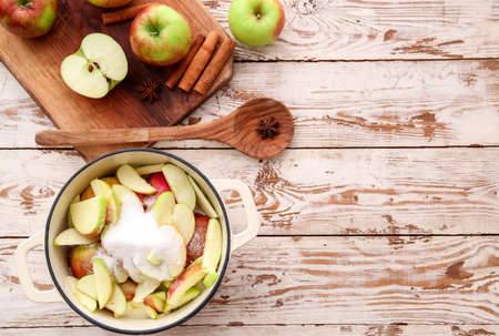 Cooking pot with cut apples and sugar on wooden backgroundの写真素材