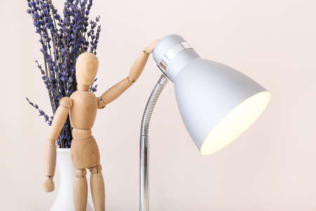 Wooden mannequin with lamp and flowers on light backgroundの写真素材