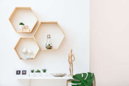 Shelves with wooden mannequin and houseplants on wall in roomの写真素材