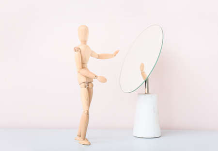 Wooden mannequin near mirror on light backgroundの写真素材