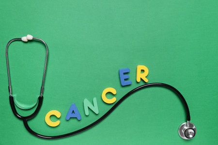 Stethoscope with word CANCER on color background