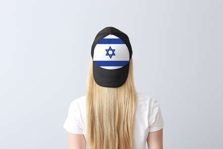 Young woman in stylish cap with Israeli flag on light backgroundの写真素材