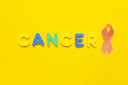 Word CANCER and golden ribbon on color backgroundの写真素材