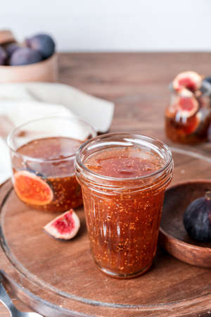 Jar of sweet fig jam on wooden table