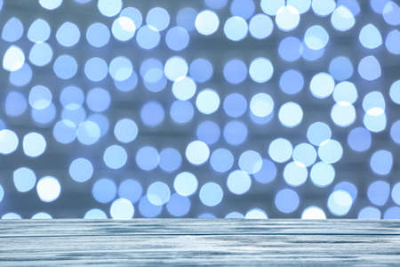 Empty wooden table against blurred Christmas lightsの写真素材