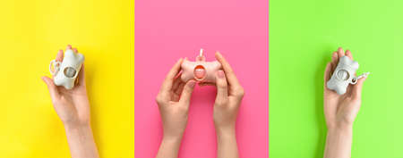 Female hands holding dispensers with pet waste bags on color background