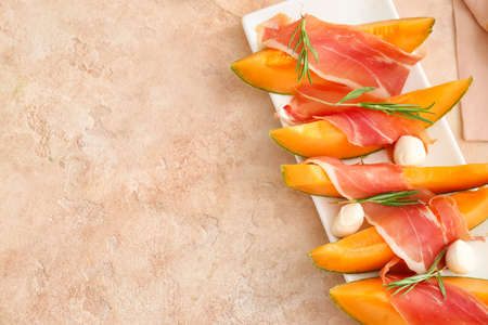 Plate with delicious melon, mozzarella and prosciutto on color backgroundの写真素材